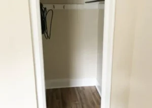 An empty closet with a wooden floor and white trim.