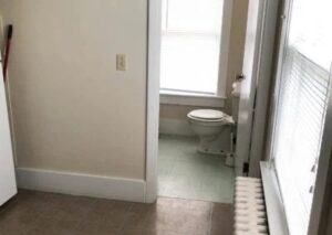 a toilet in a small bathroom with a window