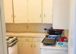 A small kitchen with white cabinets and appliances. The kitchen has a stove and countertops.